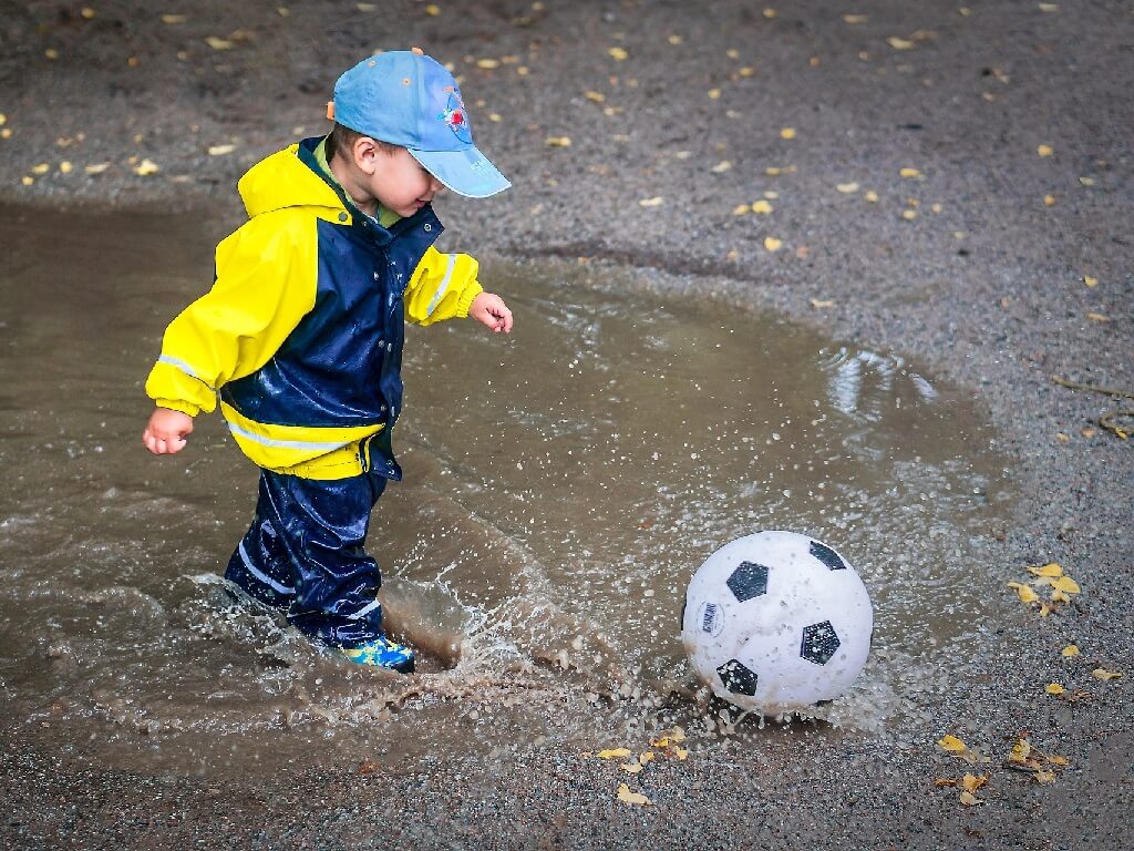 Bild kind mit Ball im matsch